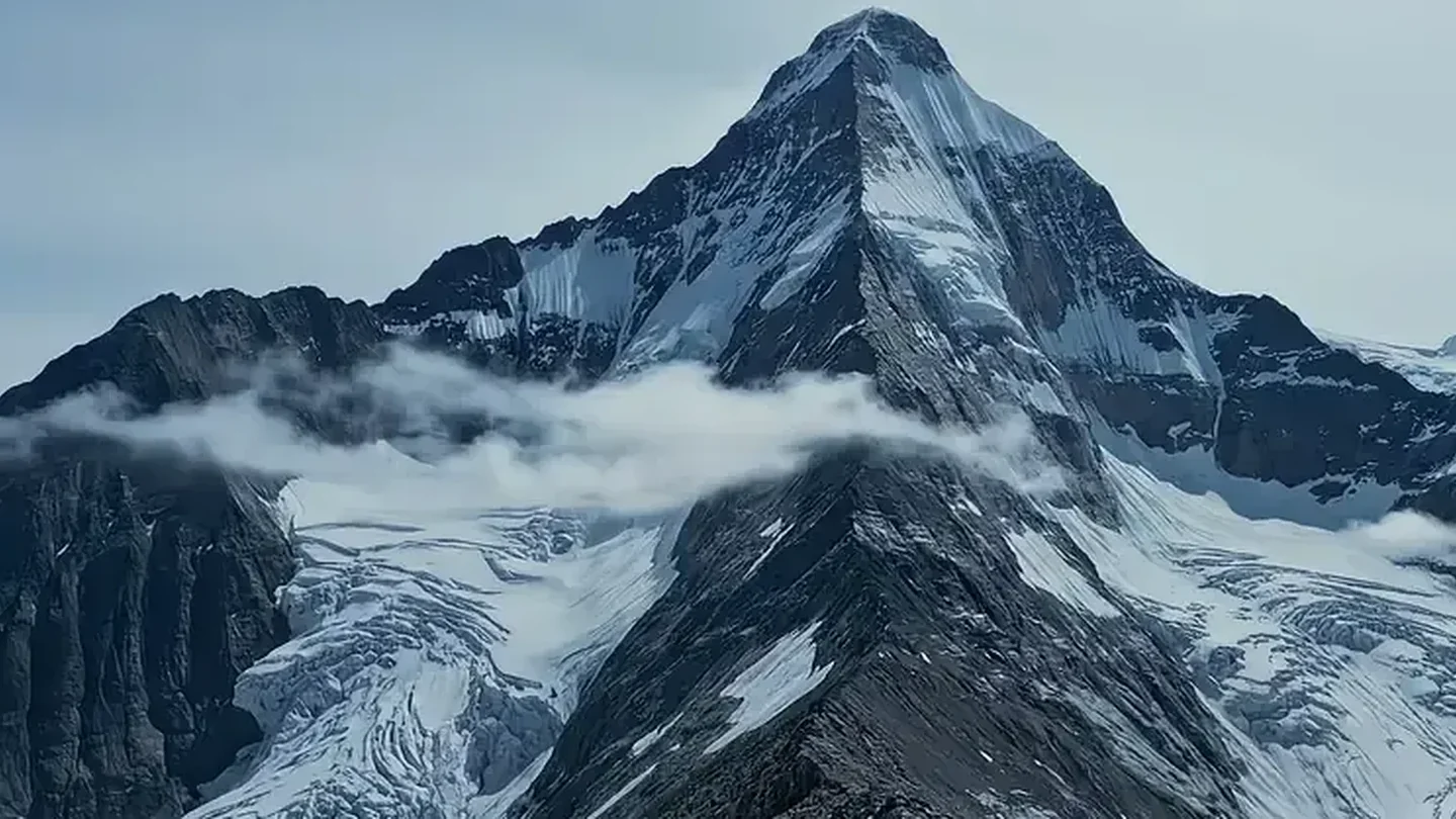 Schneebedeckter Berggipfel über einer Wolkendecke
